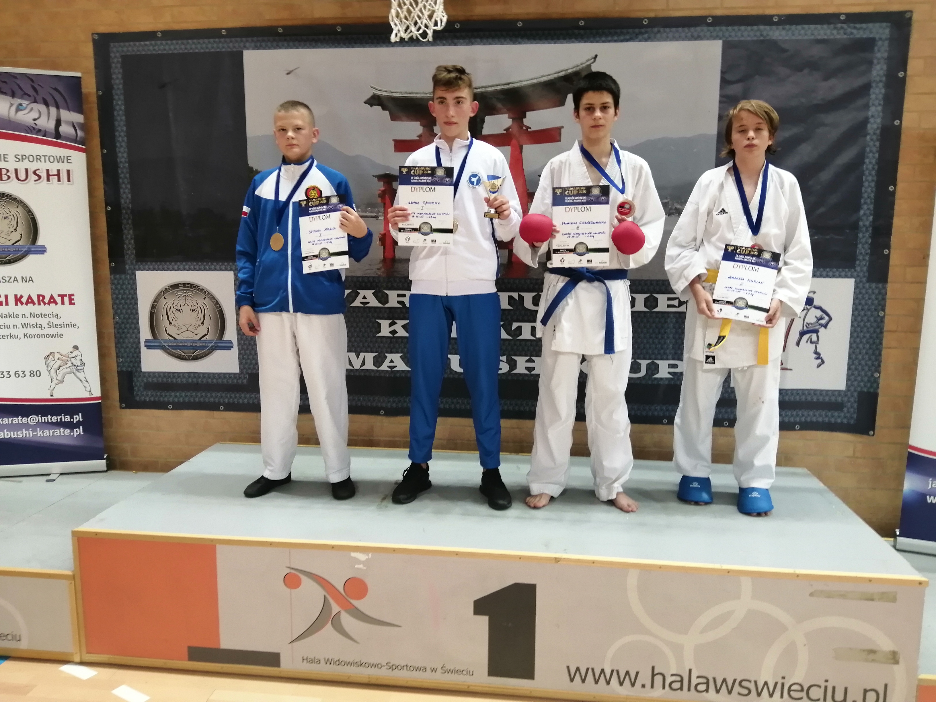 czterech zawodnikow karate na podium z medalami i dyplomami